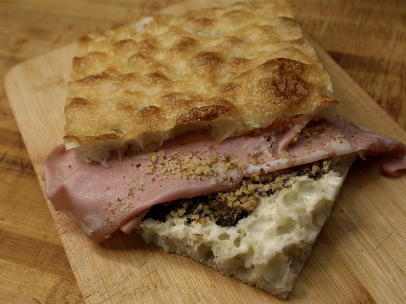 Focaccia A Moretta con mortadela sobre papel de cadros rosa